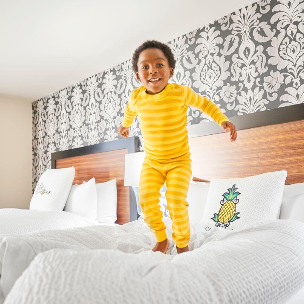 A Child Jumping On A Bed